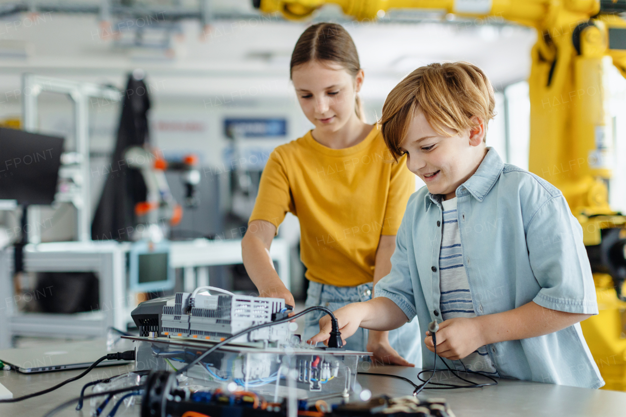 Two classmates working together on circuit board, building robot in an after-school robotics club. Children learning robotics in Elementary school.