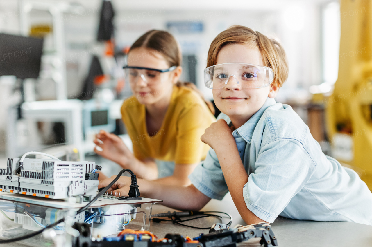 Two classmates working togeter on circuit board, building robot in an after-school robotics club. Children learning robotics in Elementary school.