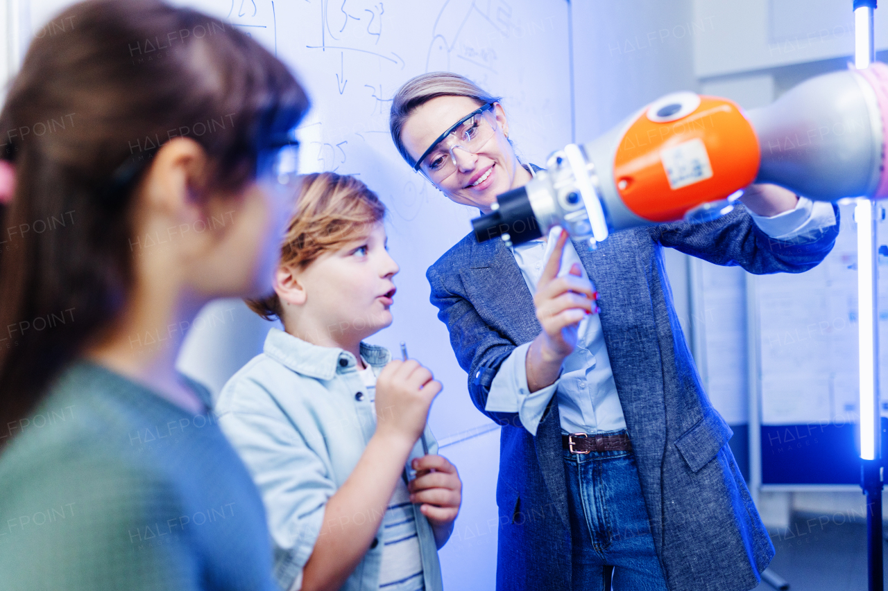 Mom, son and daughter during take your kid to work day, encouraging them in career in robotics, showing robotic arm. Field trip to real robotics laboratory. Real scientist talking to schoolboy.