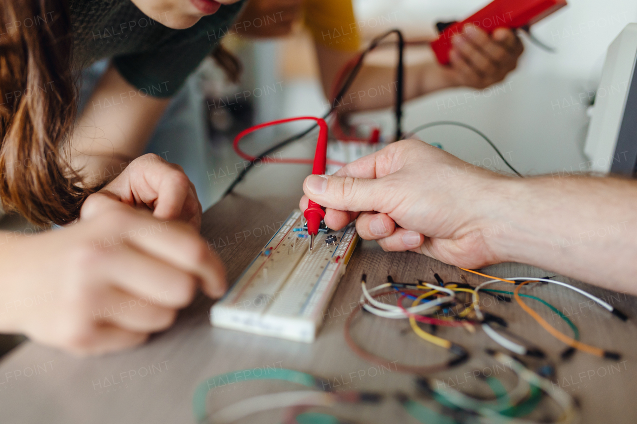 Two classmates working together on circuit board, building robot in an after-school robotics club. Children learning robotics in Elementary school.