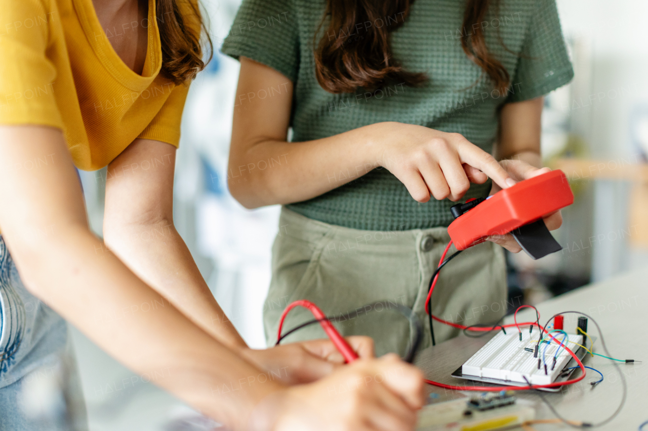 School girls working on circuit board of small robot, building robotic car in after-school robotics club. Children learning robotics in Elementary school. Girls in science, STEM.