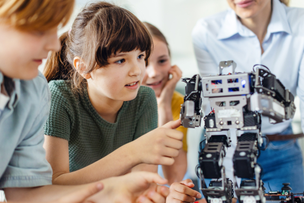 Children learning robotics in Elementary school. Young students building robot in after school robotics club. Field trip to real robotics laboratory.