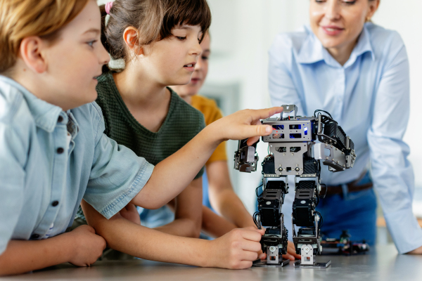 Children learning robotics in Elementary school. Young students building robot in after school robotics club. Field trip to real robotics laboratory.