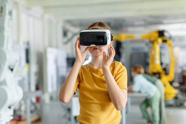 Portrait of schoolgirl with VR headset on head. Children learning robotics in Elementary school, using modern technology, virtual reality. Girls in science.