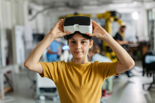 Portrait of schoolgirl with VR headset on head. Children learning robotics in Elementary school, using modern technology, virtual reality. Girls in science.