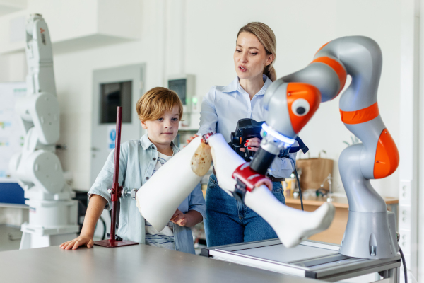 Mom and boy during take your kid to work day, encouraging children in career in robotics. Field trip to real robotics laboratory. Real scientist talking to schoolboy.