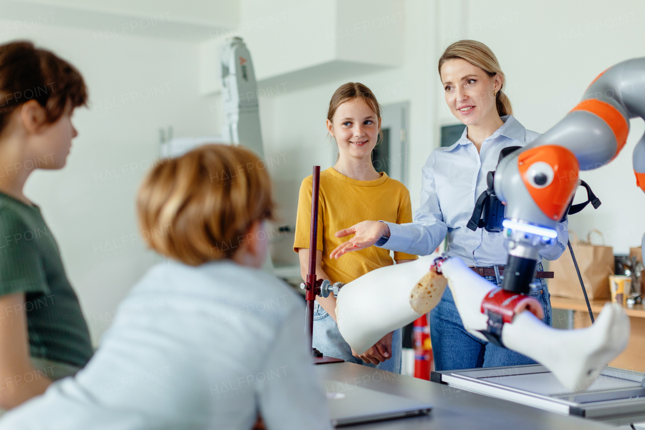 Field trip to real robotics laboratory, encouraging children in career in robotics. Real scientist talking with young students, showing them a robotic arm.