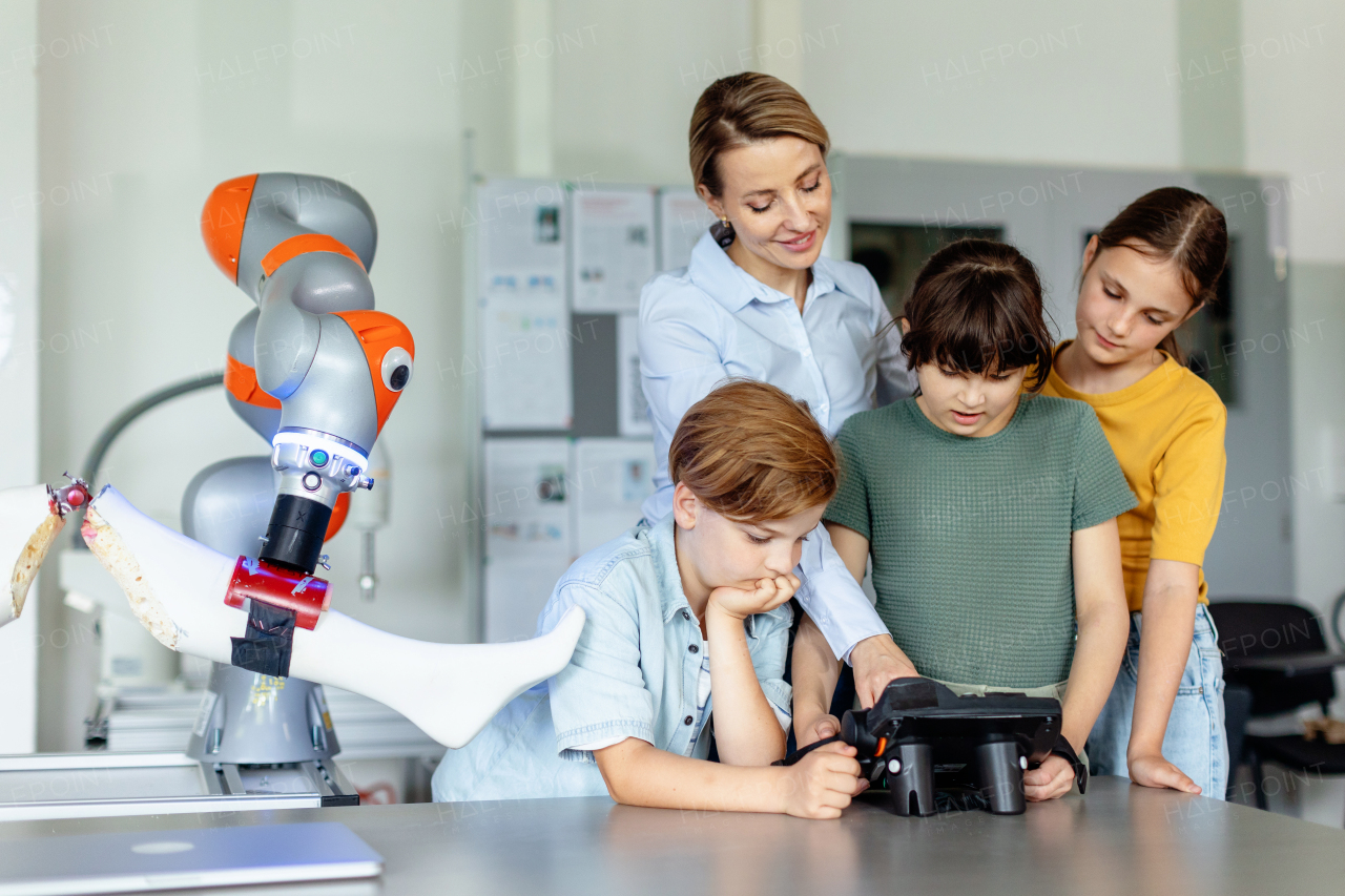 Field trip to real robotics laboratory, encouraging children in career in robotics. Real scientist talking with young students, showing them a robotic arm.