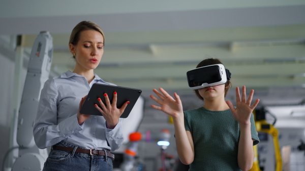 Video of schoolgril with VR headset on head and teacher with tablet. Children learning robotics in Elementary school, using modern technology, virtual reality. Girls in science.