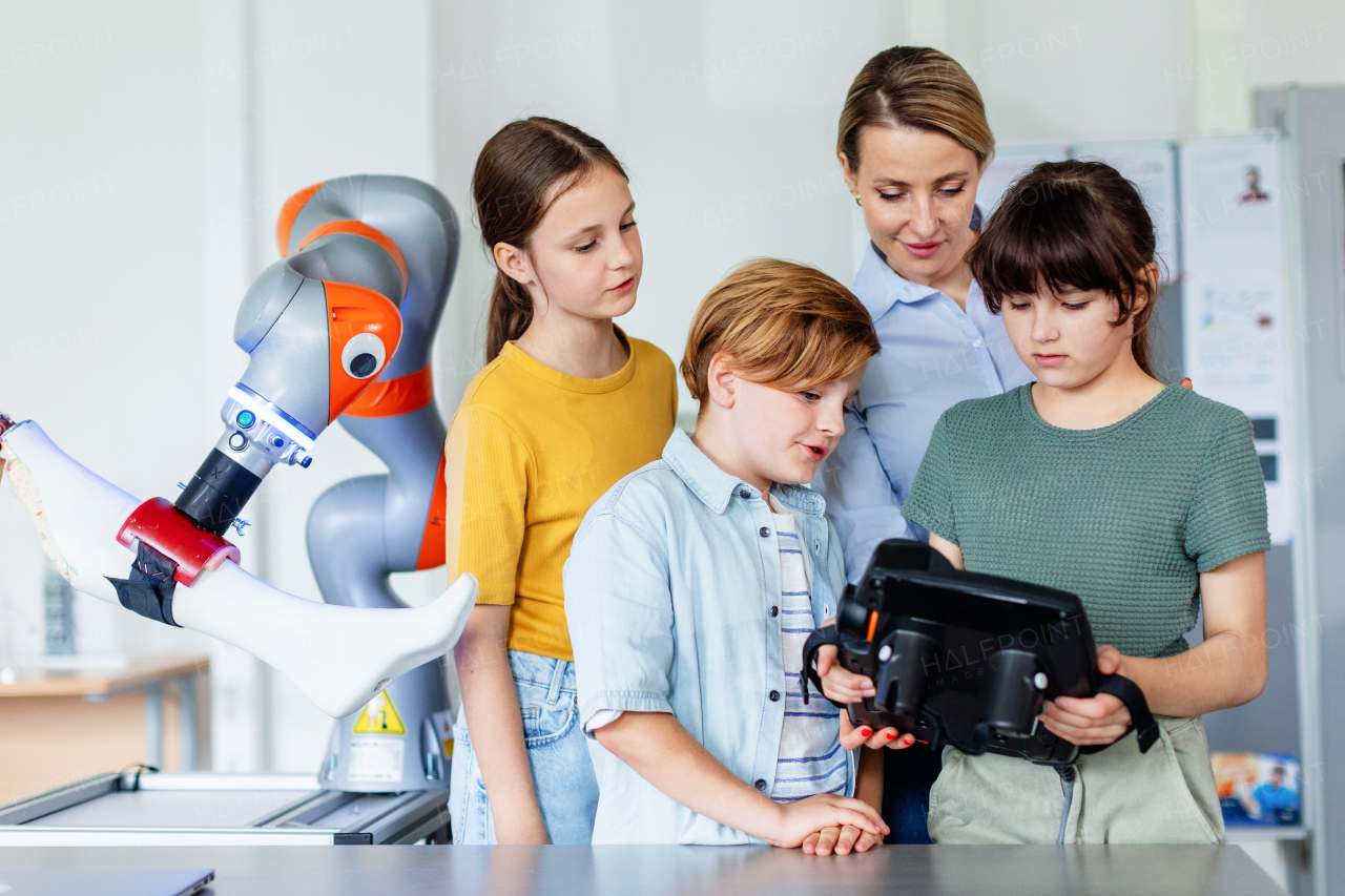 Field trip to real robotics laboratory, encouraging children in career in robotics. Real scientist talking with young students, showing them a robotic arm.