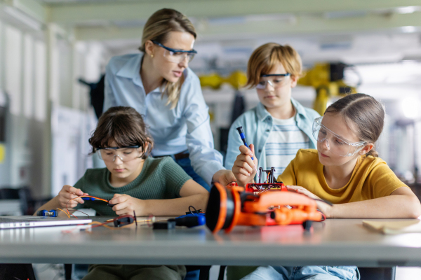 Children learning robotics in Elementary school. Young students building robot in after school robotics club. Field trip to real robotics laboratory.