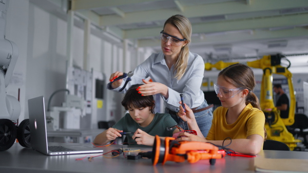 Children learning robotics in Elementary school. Young students building robot in after school robotics club. Field trip to real robotics laboratory.