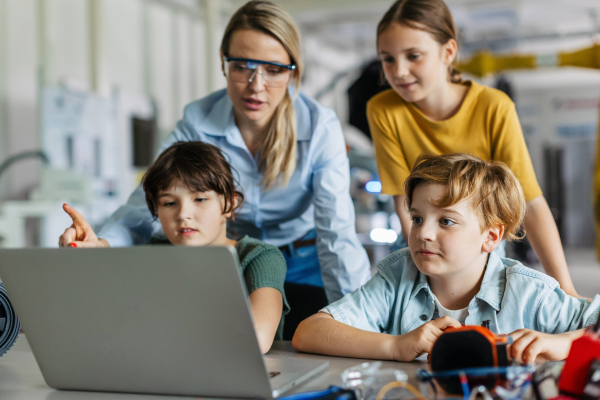 Children learning robotics in Elementary school. Young students programming, building robot in after school robotics club. Field trip to real robotics laboratory.