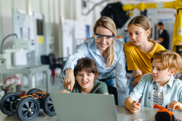 Children learning robotics in Elementary school. Young students programming, building robot in after school robotics club. Field trip to real robotics laboratory.