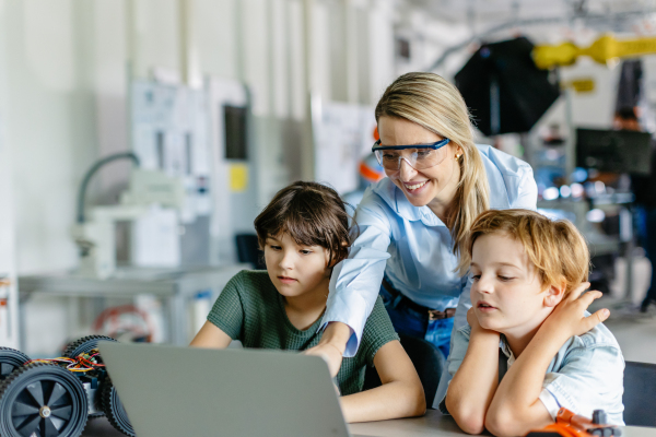 Children learning robotics in Elementary school. Young students programming, building robot in after school robotics club. Field trip to real robotics laboratory.