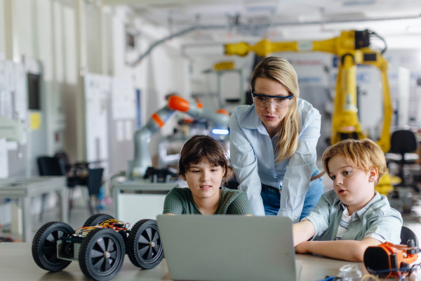 Children learning robotics in Elementary school. Young students programming, building robot in after school robotics club. Field trip to real robotics laboratory.