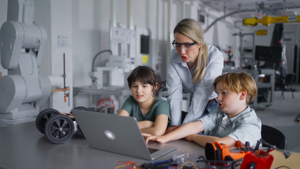 Children learning robotics in Elementary school. Young students programming, building robot in after school robotics club. Field trip to real robotics laboratory.