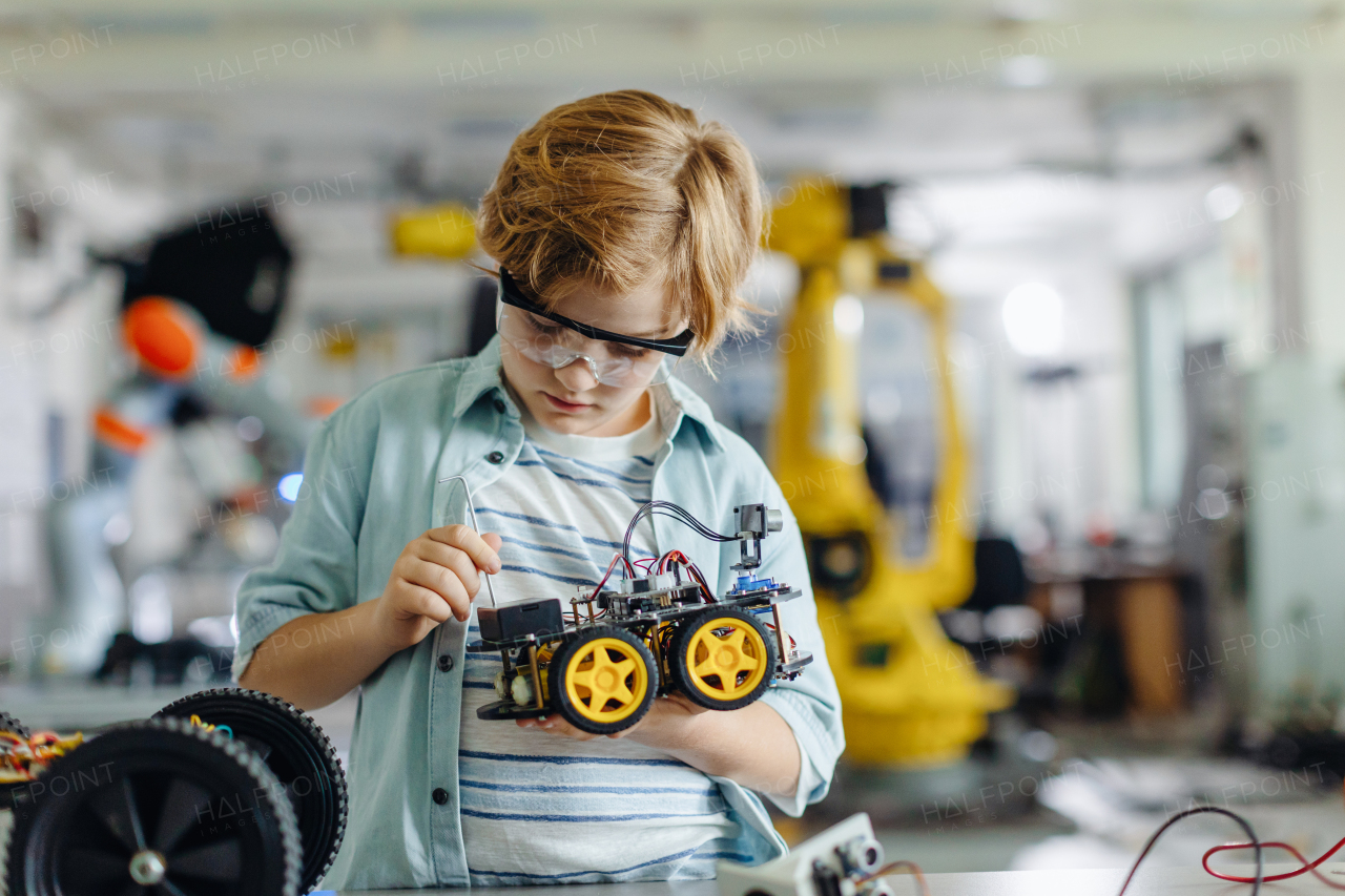 Portrait of focused schoolboy building robotic car in after-school robotics club. Children learning robotics in Elementary school. Science for kids.