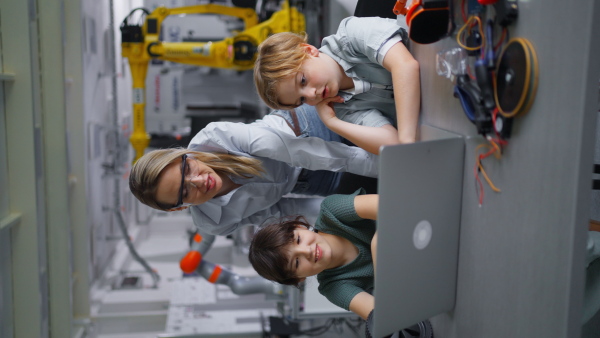 Children learning robotics in Elementary school. Young students programming, building robot in after school robotics club. Field trip to real robotics laboratory. Vertical view.