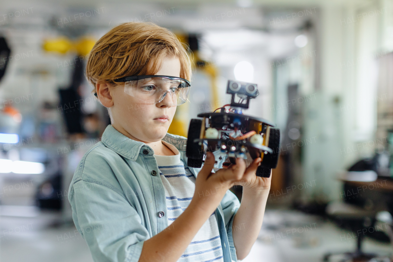 Portrait of focused schoolboy building robotic car in after-school robotics club. Children learning robotics in Elementary school. Science for kids.