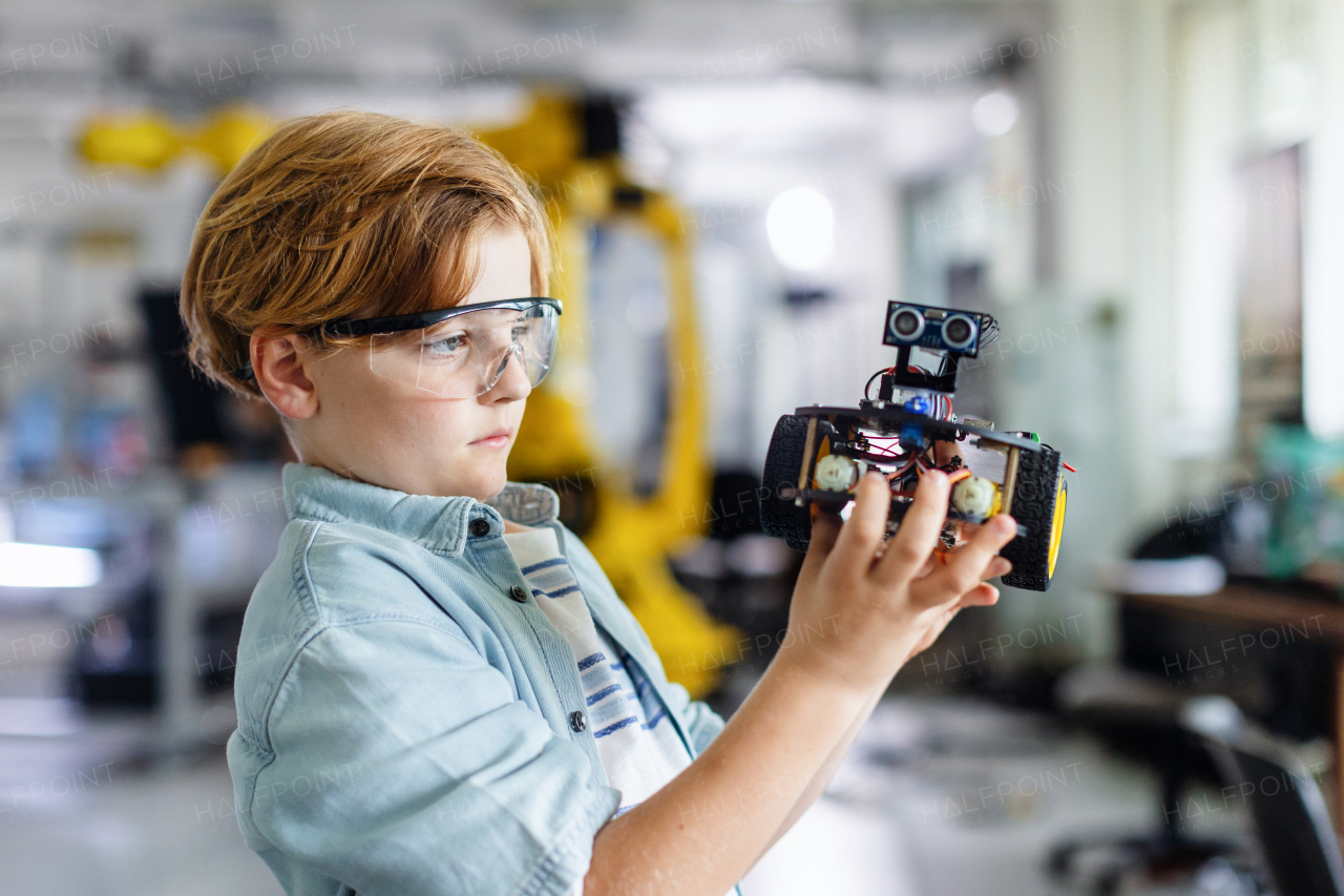 Portrait of focused schoolboy building robotic car in after-school robotics club. Children learning robotics in Elementary school. Science for kids.