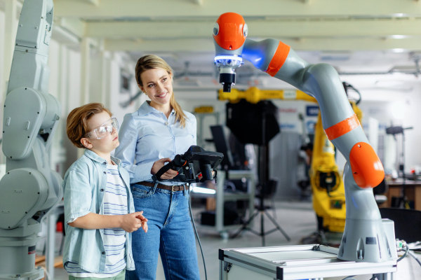 Mom and boy during take your kid to work day, encouraging children in career in robotics. Field trip to real robotics laboratory. Real scientist talking to schoolboy.