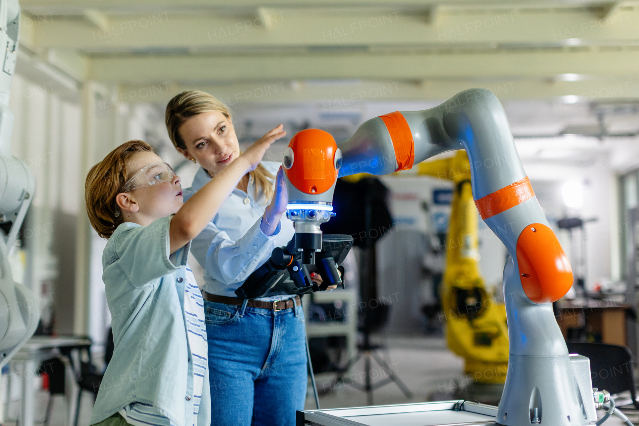 Mom and boy during take your kid to work day, encouraging children in career in robotics. Field trip to real robotics laboratory. Real scientist talking to schoolboy.