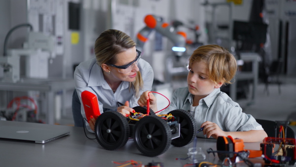 Mom and boy during take your kid to work day, encouraging children in career in robotics. Field trip to real robotics laboratory. Real scientist talking to schoolboy.