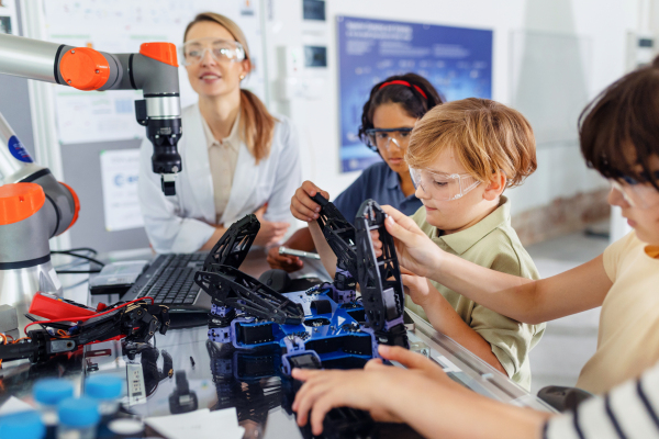 Children learning robotics in Elementary school. Young students building robot in after school robotics club. Field trip to real robotics laboratory.