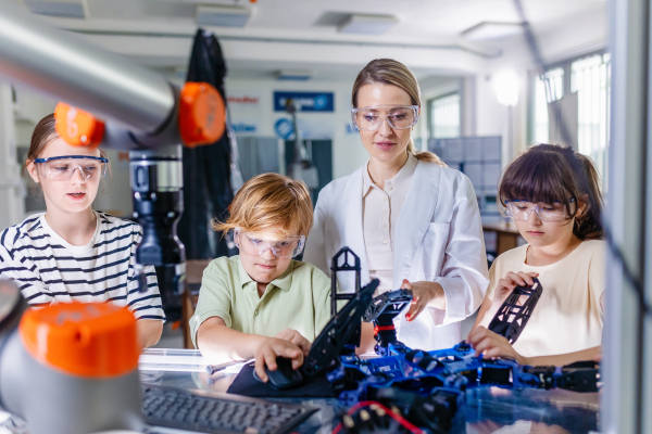 Children learning robotics in Elementary school. Young students building robot in after school robotics club. Field trip to real robotics laboratory.