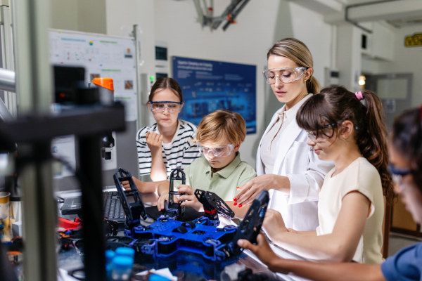 Children learning robotics in Elementary school. Young students programming, building robot in after school robotics club. Field trip to real robotics laboratory.