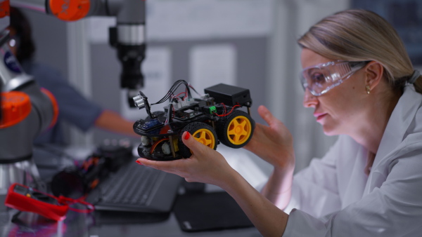 Female teacher helping young schoolboy to build robot kit in after-school robotics club. Children learning robotics in Elementary school. Science for kids. STEM.