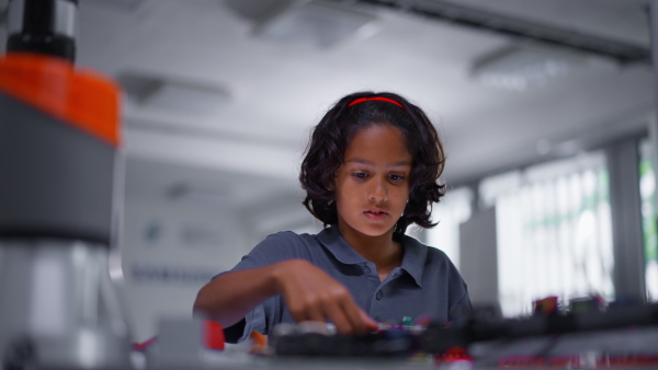 Portrait of focused schoolboy building robot in after-school robotics club. Children learning robotics in Elementary school. Science for kids.