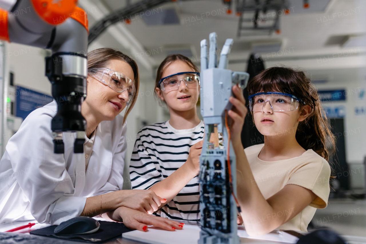 Mom and daughters during take your kid to work day, encouraging them in career in robotics. Field trip to real robotics laboratory. Real scientist talking to girls, showing them prosthetic robot hand.