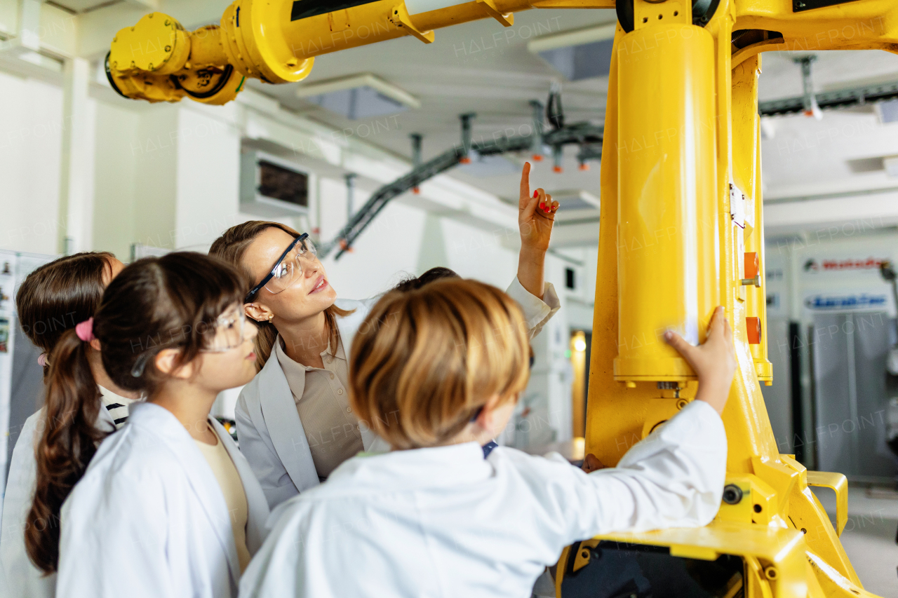 Field trip to real robotics laboratory, encouraging children in career in robotics. Real scientist talking with young students, showing them a robotic arm.