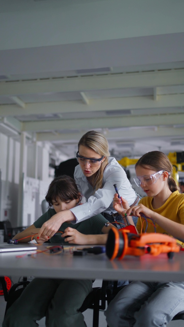 Children learning robotics in Elementary school. Young students building robot in after school robotics club. Field trip to real robotics laboratory.