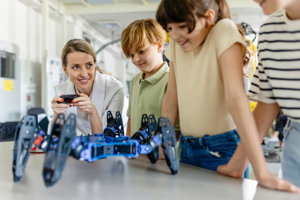 Children learning robotics in Elementary school. Young students programming, building robot in after school robotics club. Field trip to real robotics laboratory.