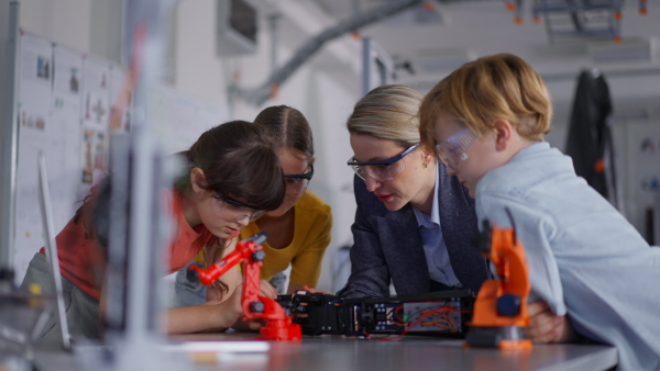 Children learning robotics in Elementary school. Young students building robot in after school robotics club. Field trip to real robotics laboratory.