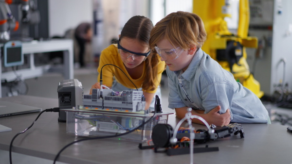 Two classmates working togeter on circuit board, building robot in an after-school robotics club. Children learning robotics in Elementary school.