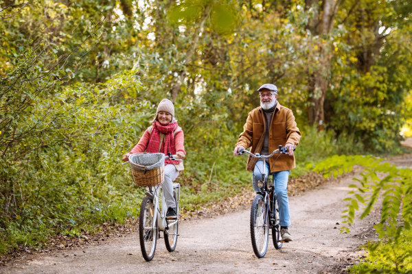 Beautiful elderly couple on bike ride in the forest. Seniors in love cycling through autumn nature, enjoying peaceful moment.