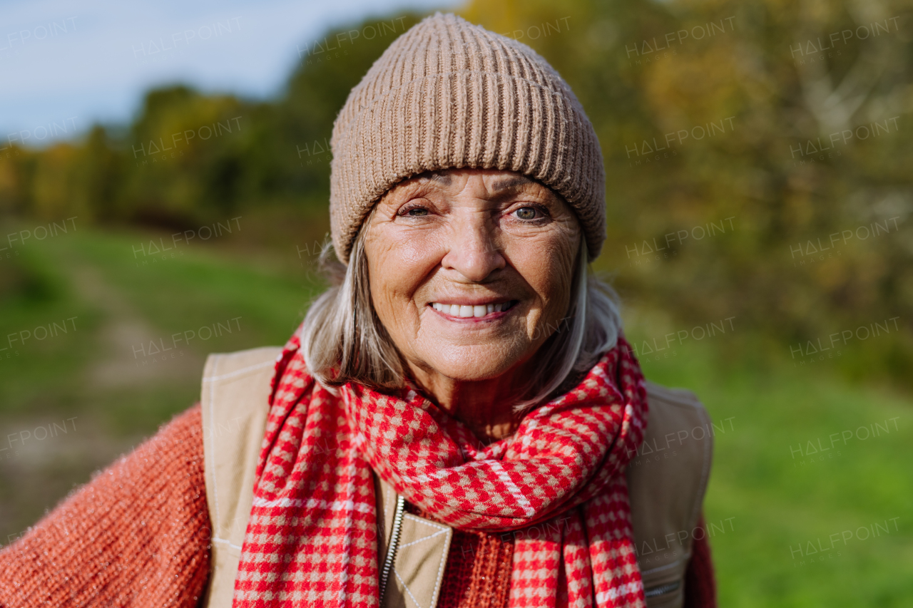 Portrait of beautiful older woman with a gray hair. Female senior standing outdoors in nature, looking at camera, smiling.