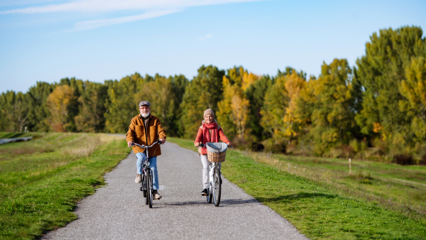 Beautiful elderly couple on bike ride. Seniors in love cycling through autumn nature, enjoying peaceful moment.