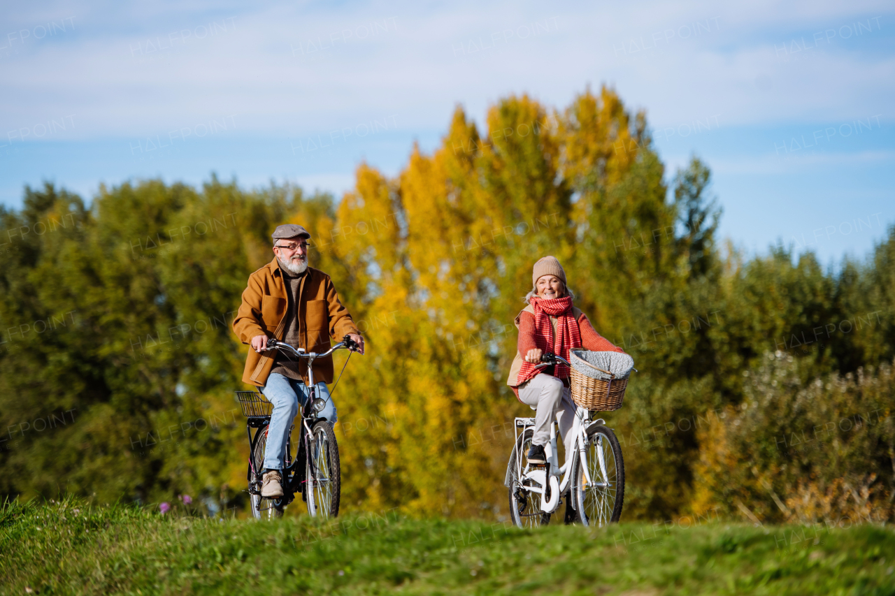 Beautiful elderly couple on bike ride. Seniors in love cycling through autumn nature, enjoying peaceful moment.