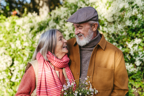 Portrait of beautiful senior couple outdoors in an autumn garden. Elderly husband and wife looking at each other lovingly