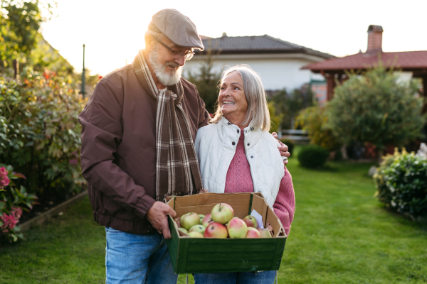 Portrait of beautiful senior couple outdoors in an autumn garden. Elderly husband and wife looking at each other lovingly