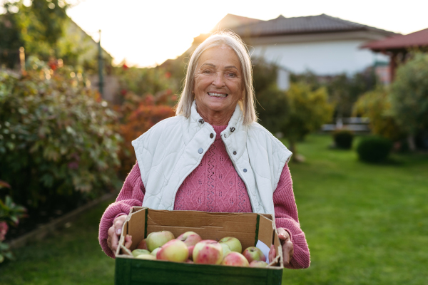 Portrait of beautiful senior woman outdoors in an autumn garden. Elderly husband and wife looking at each other lovingly