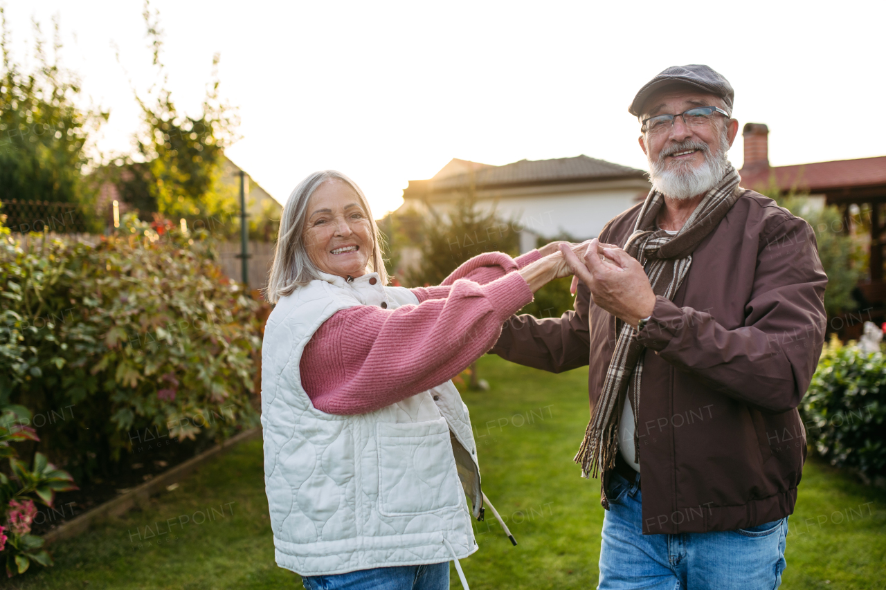 Portrait of beautiful senior couple outdoors in an autumn garden. Elderly husband and wife having fun together while dancing.