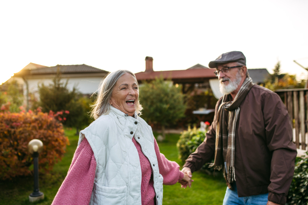 Portrait of beautiful senior couple outdoors in an autumn garden. Elderly husband and wife having fun together and laughing.