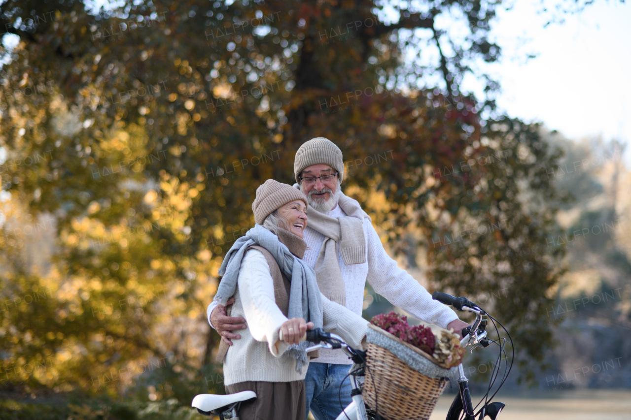 Elderly couple on walk in park, pushing their bikes side by side. Seniors in love on stroll through autumn city, enjoying a peaceful moment.