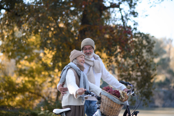 Elderly couple on walk in park, pushing their bikes side by side. Seniors in love on stroll through autumn city, enjoying a peaceful moment.